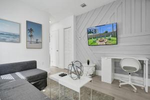 a living room with a couch and a tv on the wall at Palm Breeze Retreat in Hollywood