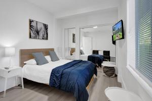 a bedroom with two beds and a flat screen tv at Palm Breeze Retreat in Hollywood