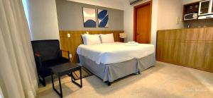 a small bedroom with a bed and a chair at Confortável Flat em Brasília-BR in Brasília