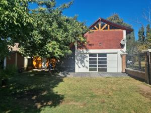 a house with a white garage and a tree at Casa quincho en plottier in Plottier
