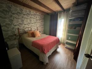 una camera da letto con un letto con una coperta rossa di Amuleto Cabañas, Bella Vista, Maldonado a Bella Vista