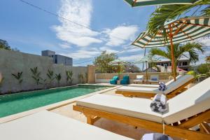 a swimming pool with lounge chairs and an umbrella at Casa de Capulet in Labuan Bajo