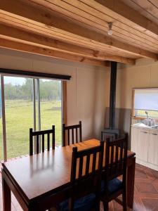a dining room with a table and a wood stove at Cabaña rivera del Captrén in Curacautín