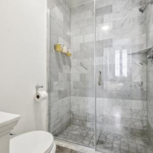 een witte badkamer met een douche en een toilet bij Roami at St. Helene in New Orleans +26 foto's