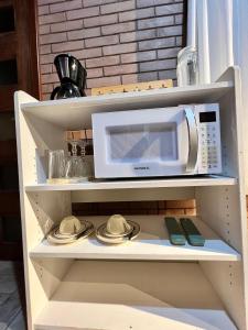 een magnetron die bovenop een plank staat bij Flat Girassol Santo Antônio do Pinhal in Santo Antônio do Pinhal