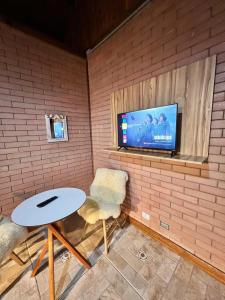 een kamer met een tafel en een tv aan een bakstenen muur bij Flat Girassol Santo Antônio do Pinhal in Santo Antônio do Pinhal