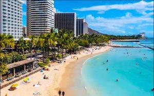 a beach with people in the water and buildings at Sweet Blue Hawaii in Honolulu