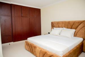 a bedroom with a large bed with wooden cabinets at A Beautiful home, Kanombe, Nyarugunga in Kigali