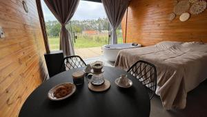 a room with a table and a bed and a tub at Chalé Tiny house com banheira e lareira in Osório