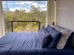 a bed in a bedroom with a large window at Casa Borba Chalé encantador in Alto Paraíso de Goiás