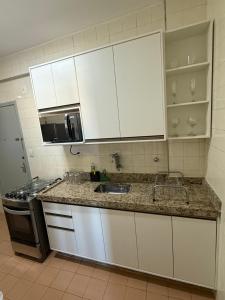 a kitchen with white cabinets and a sink at Edificio na rua do Parque das Aguas in São Lourenço