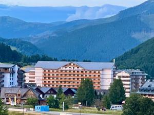 a large hotel with mountains in the background at Havasi View Donovaly - 2 Bedrooms, Mountain View, Garage, 2 WC, Balcony, Dishwasher, Guitar, 164 cm TV, Netflix in Donovaly