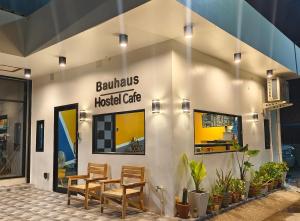 een gebouw met een tafel en stoelen ervoor bij Bauhaus Hostel Cafe in Don Sak