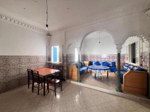 a dining room with a table and blue chairs at Plage krikiya in Asilah