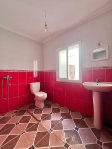 a red bathroom with a toilet and a sink at Plage krikiya in Asilah
