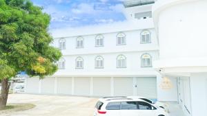 加拉班snowwhite castle hotel的一栋白色建筑，前面停着一辆白色汽车