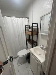 a white bathroom with a toilet and a sink at Soothing bungalow with AC in Pompano in Pompano Beach