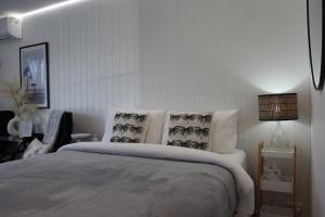a white bedroom with a bed with pillows at Dee Why Beach - Surfrider Studio 8 in Deewhy