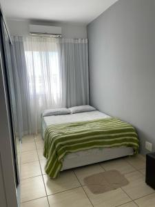 a bedroom with a bed with a green blanket on it at O melhor e + aconchegante AP de SPA (custo/benefício) in São Pedro da Aldeia