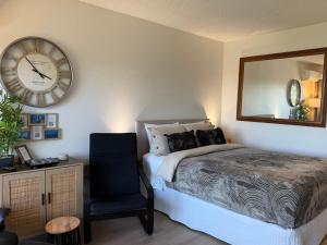 a bedroom with a bed and a clock and a chair at Dee Why Beach - Surfrider Studio 22 in Deewhy