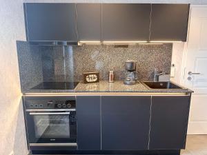 a kitchen with a black stove and a sink at WILD&COZY Apartment mit moderner Küche & Terrasse in Blankenburg