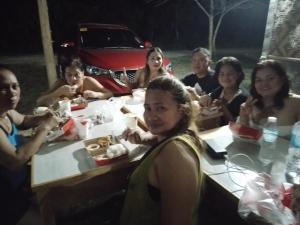 a group of people sitting at a table eating food at NELU GUEST HOUSE in Panglao Island