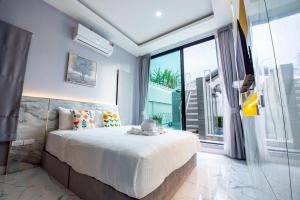a bedroom with a large bed and a large window at Phirom one pattaya poolvilla in Nong Prue +42 photos