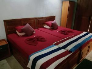 a bed with a red blanket and pillows on it at Thehideout kurunegala in Kurunegala