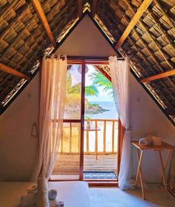 a bedroom with a large window with a view of the ocean at Beach Front Cabana 1, Puraran Surf Resort in Sampong