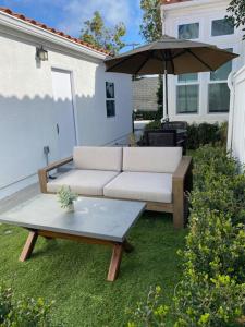 a couch and an umbrella in a yard at Newly built Guest House near beaches in Costa Mesa