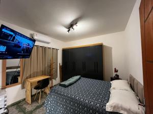 多拉杜斯Loft Mobiliado e Bem Localizado com Ar condicionado C的一间卧室，里面有一张床和一台平板电视