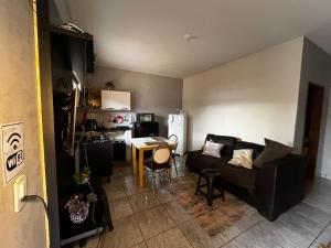 a living room with a black couch and a kitchen at Loft individual Mobiliado com Ar-condicionado B in Dourados +18 photos