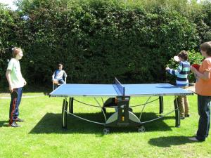 a group of people standing around a ping pong table at Tollgate Cottages Bed and Breakfast in Freshwater