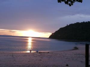 Una puesta de sol en una playa con la puesta del sol en Moonshine Phayam beach resort & restaurant, en Ranong