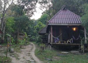 Una pequeña casa con una hamaca y un camino de tierra. en Moonshine Phayam beach resort & restaurant, en Ranong