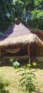 una cabaña con techo de paja en un campo en Moonshine Phayam beach resort & restaurant, en Ranong