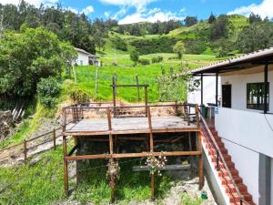 a house with a wooden deck in a field at Hotel Mahoma in El Cocuy