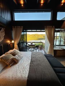 a bedroom with a large bed and a large window at Santuá - Cabana Bellagio in Rio dos Cedros