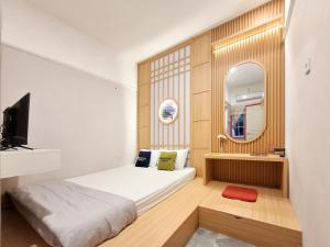 a small bedroom with a bed and a mirror at Urbanview Livy House Blitar in Karangtengah