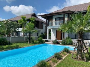 a villa with a swimming pool in front of a house at Lanna Fusion in Hang Dong