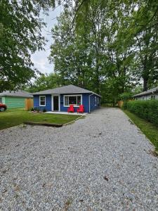 a blue house with red chairs on a gravel driveway at Cozy 3BR Cottage Near Headlands in Mentor