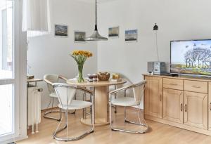 a dining room with a table and chairs and a tv at Terrassenhaus - 9 in Cuxhaven