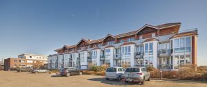Un gran edificio con coches aparcados en un estacionamiento. en Knechtsand - 441, en Cuxhaven