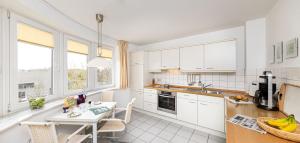 a kitchen with white cabinets and a white table and chairs at Seeterrassen - 12 in Cuxhaven