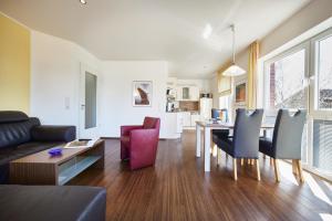 a living room with a couch and a table and chairs at Residenz Seegras - 5 in Cuxhaven