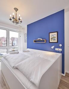 a large white bed with a blue wall at City Marina - Haus 24A in Cuxhaven
