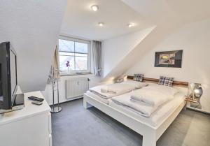 ein weißes Schlafzimmer mit einem Bett und einem Fernseher in der Unterkunft Scharhörn - 7 in Cuxhaven