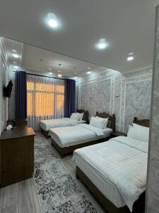 Un dormitorio con tres camas y una ventana. en Malika Sultan Hotel with National Boutique Museum, en Bukhara