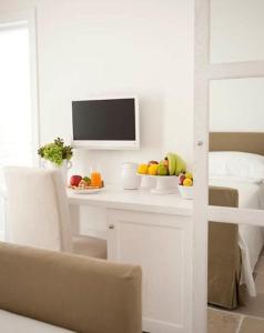 una mesa blanca con un bol de fruta y un televisor en B&B Donnapasqua, en Polignano a Mare