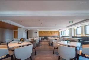 哈尔滨哈尔滨松北融创乐园亚朵X酒店的带桌子和白色椅子的餐厅